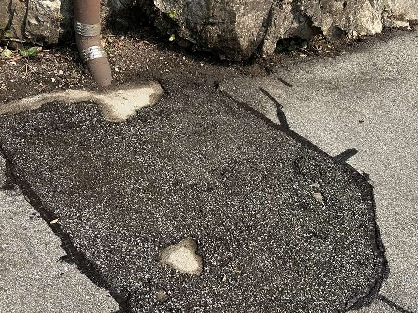 The same shoulder cut out, patched with fresh asphalt and sealed around the edge